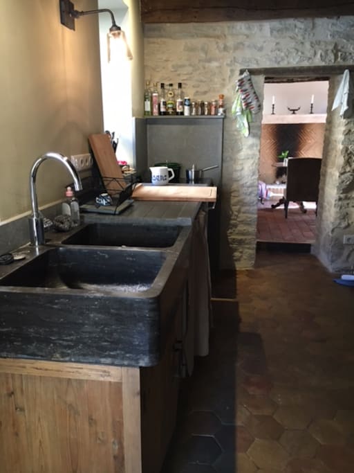 La cuisine tout confort avec plan de travail en pierre des carrière de Montagny, évier en pierre.