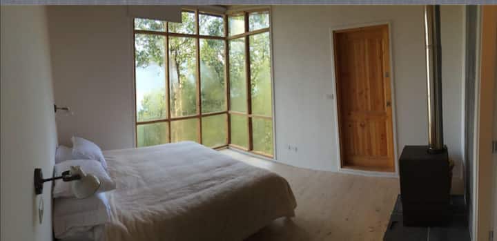 غرفة رئيسية بسرير كبير وموقد خشبي وإطلالات رائعة وحمام خاص بساونا صغيرة.