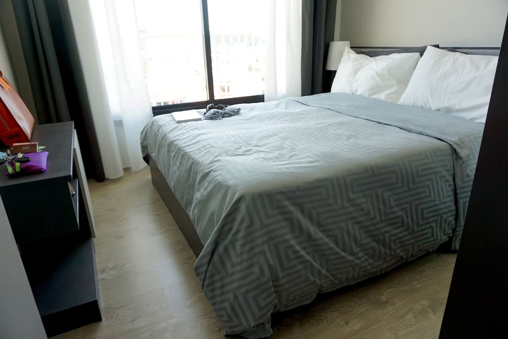 Bedroom with a queen bed and sea view over the city. Comfortable, quality bed sheets for a great night sleep.