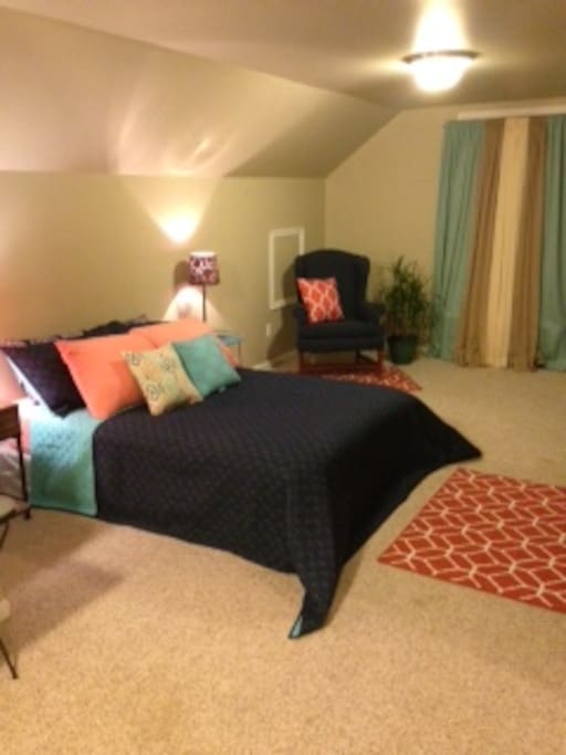 Full size bed with new bedding and seating area