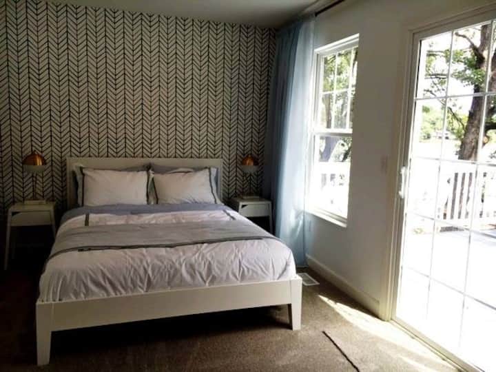 Cuarto dormitorio con cama tamaño queen, baño privado y terraza con vistas al agua.