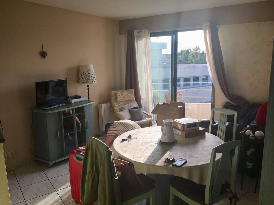 Le salon avec télé / box internet/ table de salle à manger et balcon
