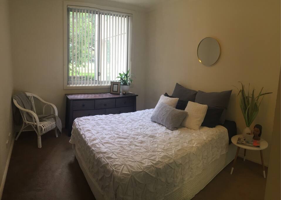 Large size bedroom with green leafy outlook and personal storage chest of drawers.