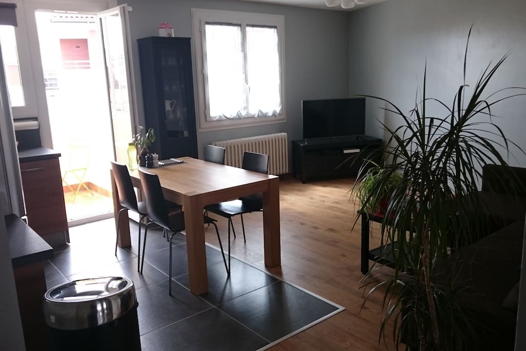 Pièce à vivre ouverte sur balcon avec table et 2 chaises
