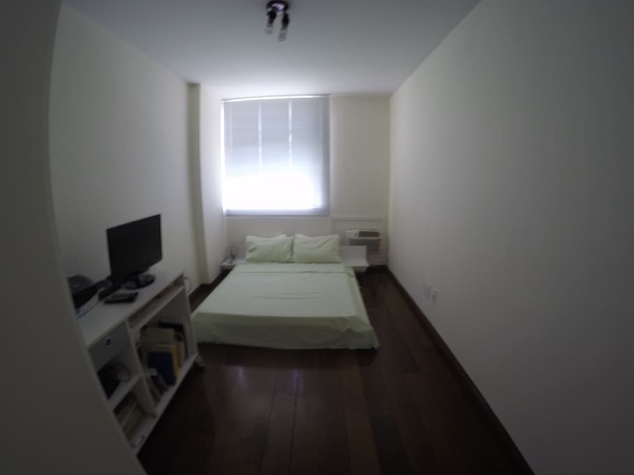 Quarto amplo com uma cama de casal e uma mesa para trabalho, uma TV, aparelho com internet Wi-Fi