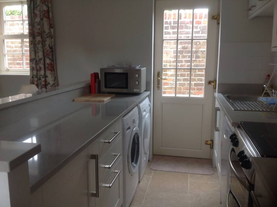 Fully equipped open plan kitchen with washing machine, dishwasher, microwave, dryer, full sized oven and gas hob