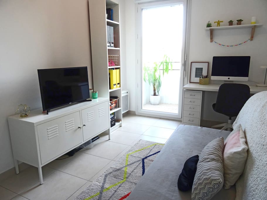 Chambre cosy avec accès sur la terrasse. canapé lit avec télévision et ordinateur.