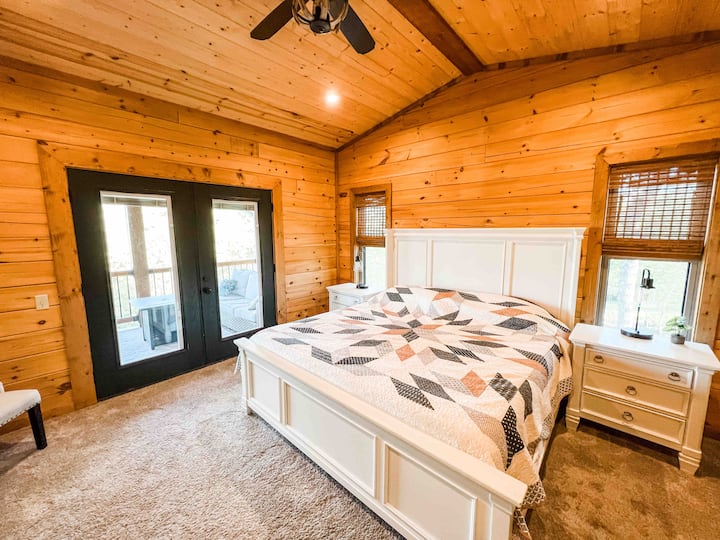 Spacious master bedroom with king bed, vaulted ceiling, private deck access, and plenty of natural light for a peaceful retreat. Double doors to deck have blinds embedded into the doors for privacy. 
