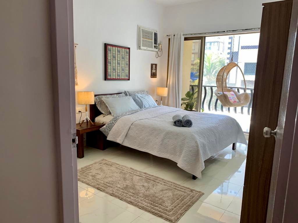 בחדר השינה 1 יש מיטת קווין סייז, מנורת לילה, מיזוג אוויר ומרפסת עם נדנדת - מושלם להירגע ולהשתחרר.