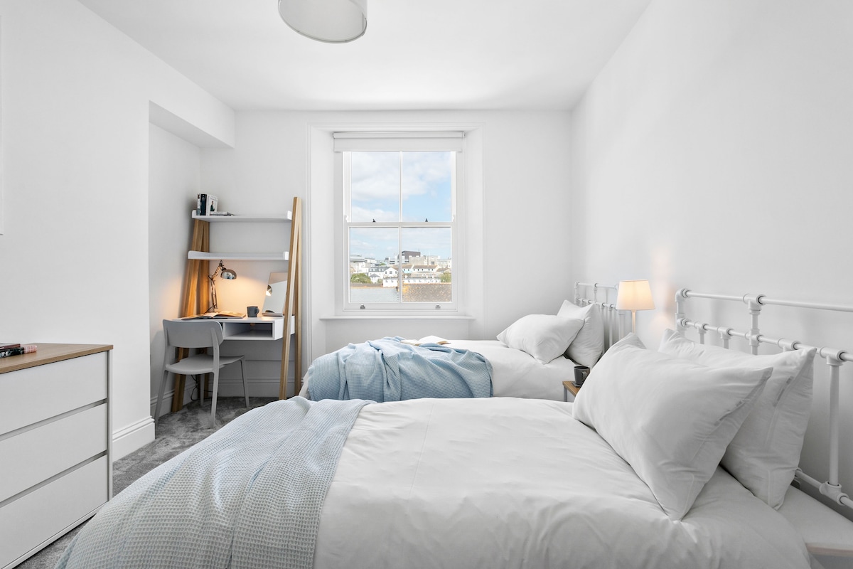 לברוח לנופש בקומה השנייה! ליהנות מחדר זוגי מרווח עם נוף פנורמי של קו הרקיע של העיר, דארטמור והמרינה. להתפנק בנוחות עם מיטות נפרדות ומזרנים היברידיים של איב. שולחן הלבשה/פינת עבודה ייעודית מחכה לכם.
