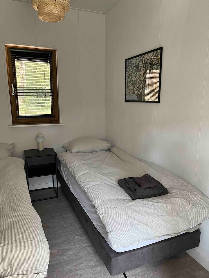 Chumba cha kulala chenye vitanda 2 vya mtu mmoja, meza kando ya kitanda na kabati la nguo lenye viango