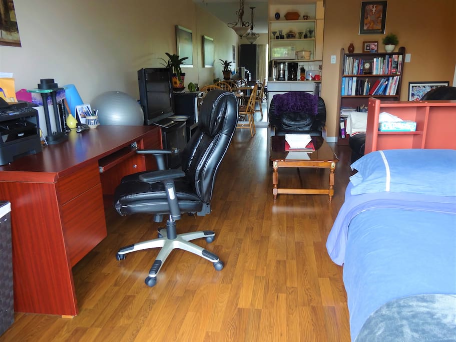 View of the living room from the bed through to the dining area. The kitchen is behind the wall with the bookcase.