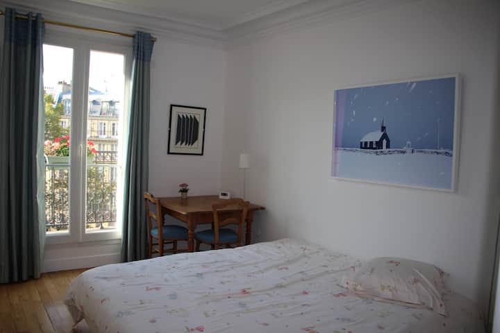 Სტუმრების ოთახი დიდი ზომის საწოლის ვერსიით, რომელიც გადაჰყურებს  მის ყვავილებიან გერანიუმებს, რომლებიც აივანს ამშვენებს 