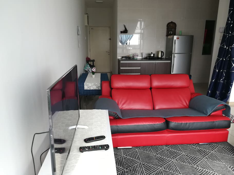 Living room with comfortable couch, air-conditioning, fan, desk, television with Astro channel.