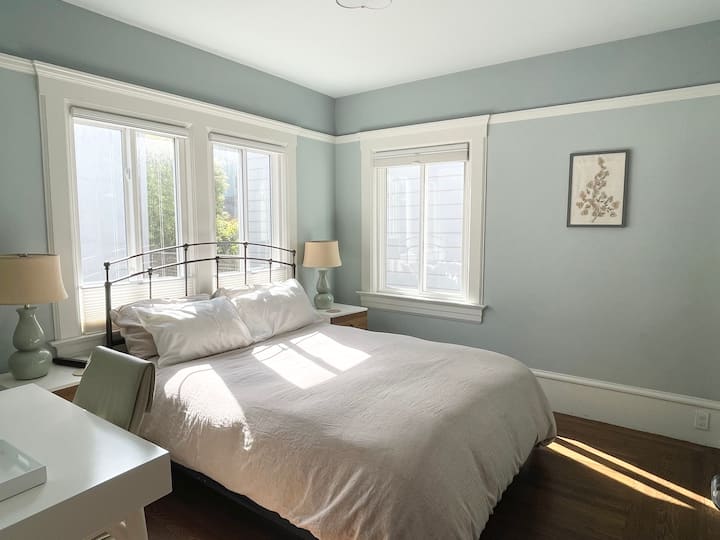 Guest suite #1 met queensize bed en eigen badkamer en meerdere ramen aan twee kanten met uitzicht op de tuin patio die voldoende ventilatie en ochtendzon bieden. 
