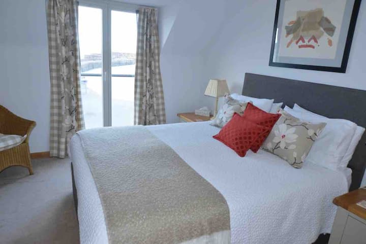 First floor bedroom with king-size bed. There is a Juliet balcony which overlooks the sea and harbour.
This bedroom has an ensuite shower room and a spacious walk in wardrobe which is good for storing luggage.