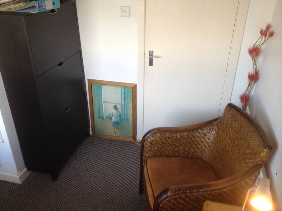 Armchair, shoe rack and door in single room
