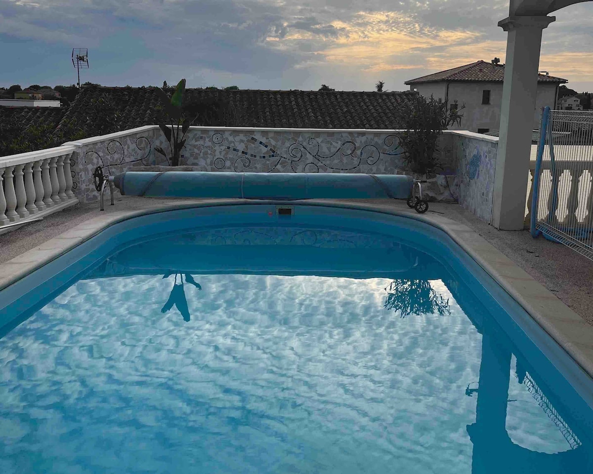 A clear blue pool reflects the evening sky, surrounded by a decorative fence for safety. The terrace is adorned with lush plants and offers a serene view, emphasizing a peaceful outdoor space for relaxation.