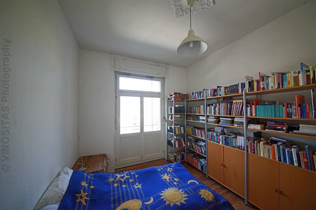 Schlafzimmer mit vielen Büchern und Zugang zum Westbalkon