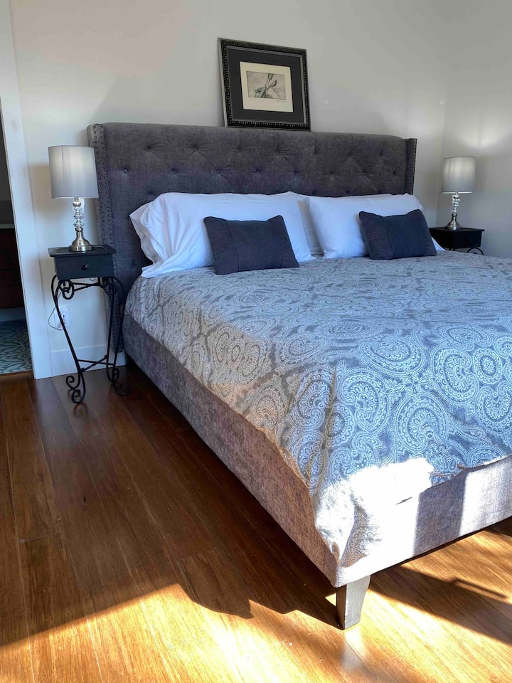 Tercer dormitorio con cama tamaño king y ventanal a la vista del jardín.