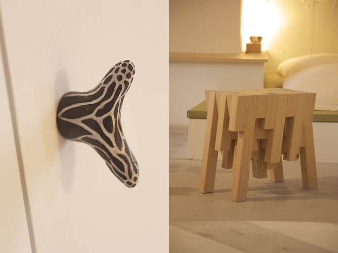 A unique drawer knob is shown, featuring an intricate black and white design. Nearby, a creatively designed wooden table with a geometric shape sits on a light-colored floor, complementing the simple and modern aesthetic of the room.