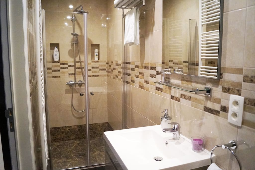 Waterfall walk-in shower with towels and brand-name toiletries.