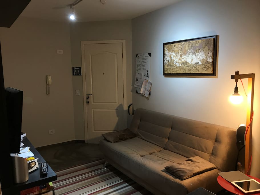 A entrada, a sala e o sofá-cama do apartamento.