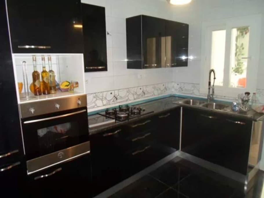 Cuisine avec bar et trois tabourets sur la droite + balcon