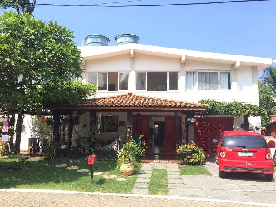 Frente da casa: varanda, garagem com vaga para quatro carros.