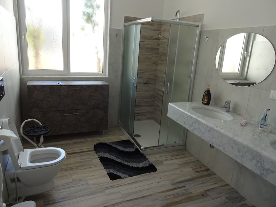 Bagno in marmo e ceramica con doppio lavabo e doccia king size con cromoterapia