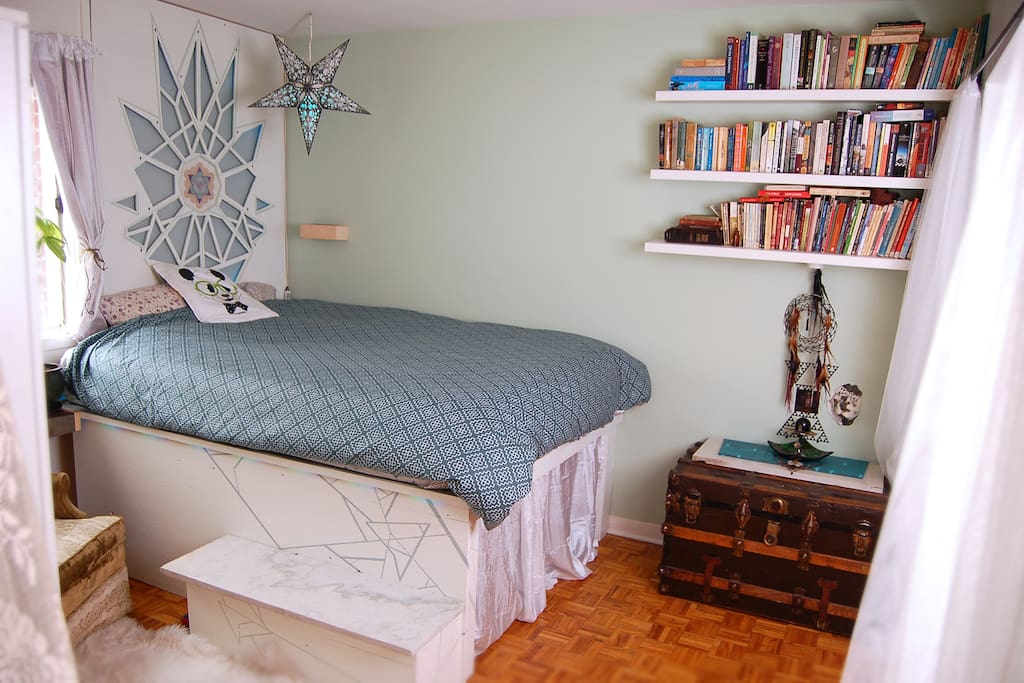 Cosy bedroom full of books and art. The headboard and edge of bed are led lined for soft, romantic lighting.