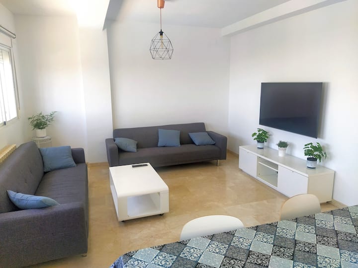Luminoso salón con estilo moderno, Smart TV y ambiente acogedor. Ideal para relajarse, disfrutar de una película o compartir momentos en familia tras un día descubriendo Granada.