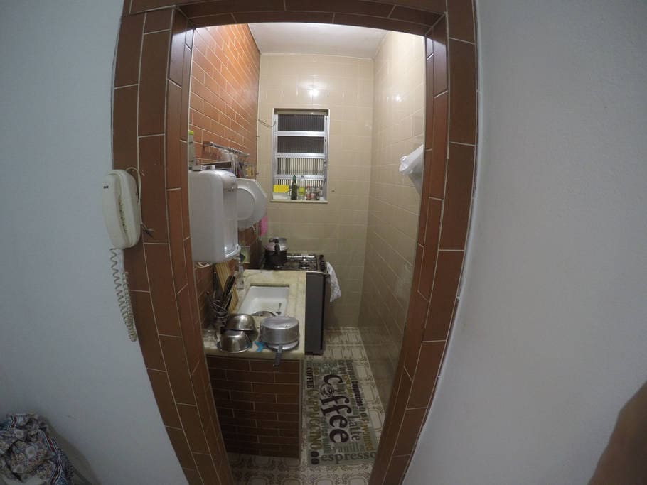 Cozinha equipada com fogão, panelas, louça e filtro de água gelada