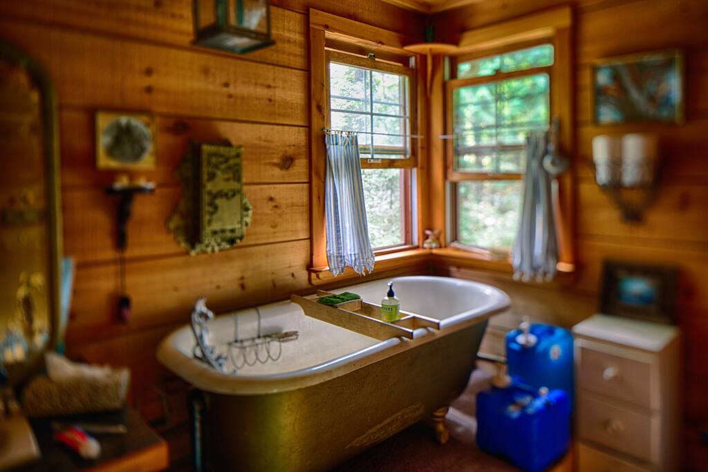 Antique clawfoot bathtub with propane water heater and low-water flush toilet. Bathroom now painted white!