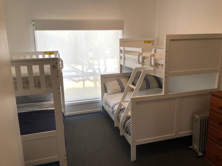 Chumba cha kulala kilicho na bunks ikiwa ni pamoja na kitanda cha watu wawili chini ya bunk moja.