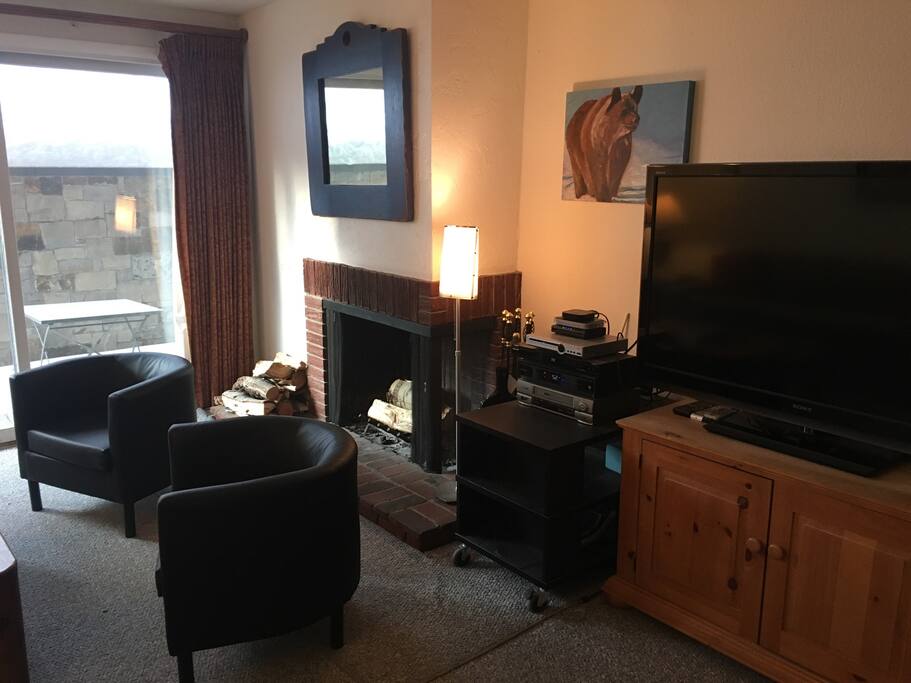Living area with wide-screen TV and wood-burning fireplace.