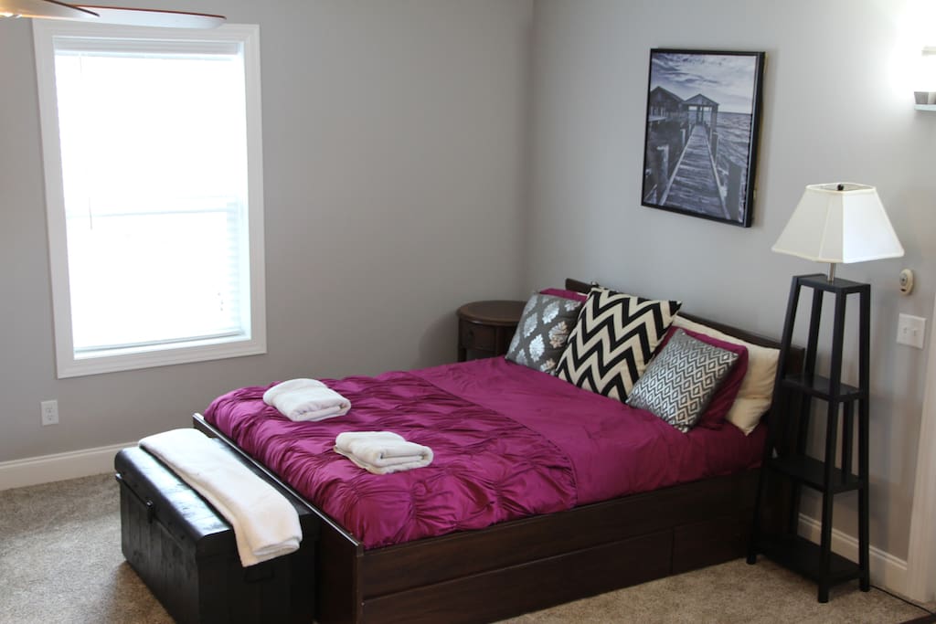 Bedroom area with a lamp, nightstand, and extra blankets