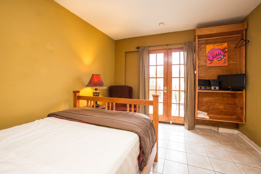 Bright bedroom area has new double bed, TV, closet , radio, sitting area