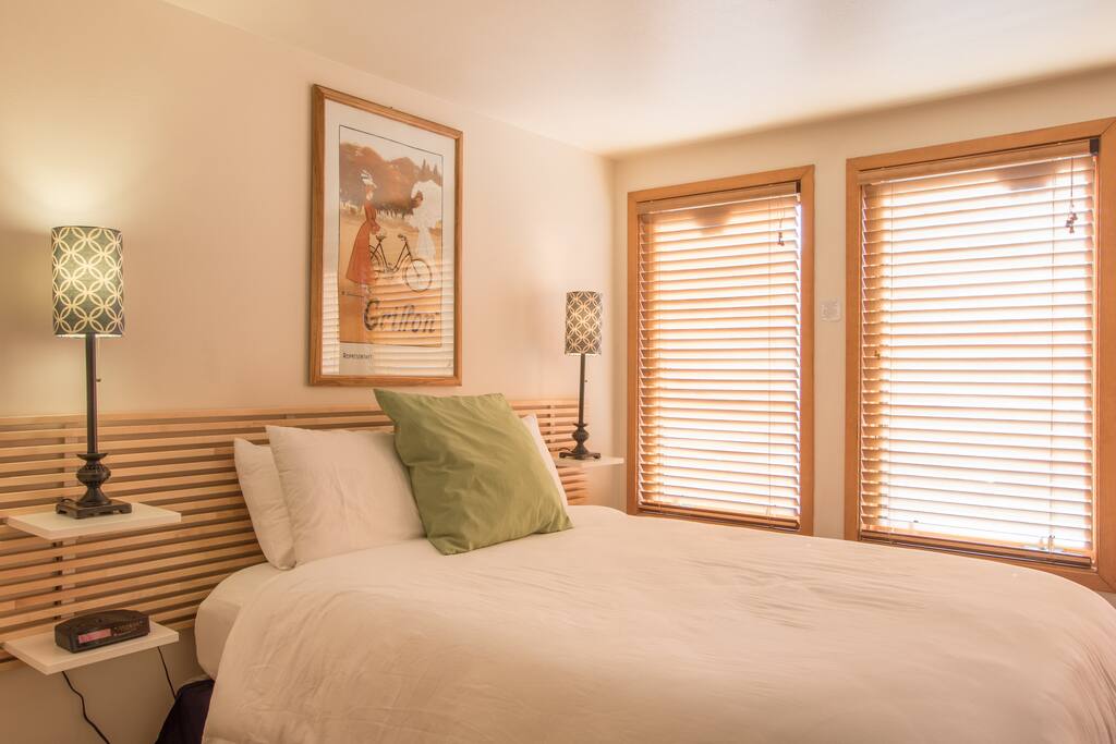 The sunlit bedroom area has a queen-sized bed