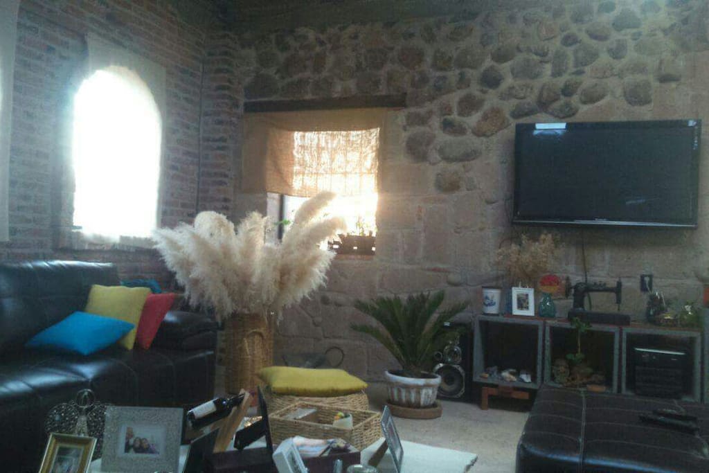 The living room with big tv and two sofas.
In the same big place a big table for 8 persons.