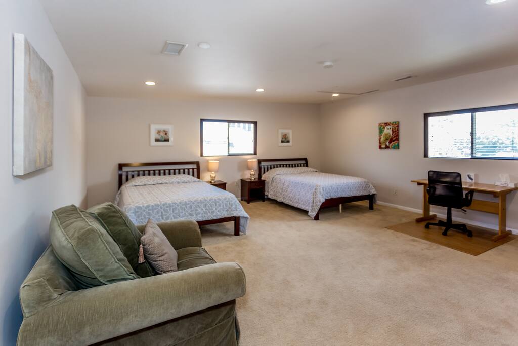 Bedroom with two queen size beds, armchair, closets, and desk.