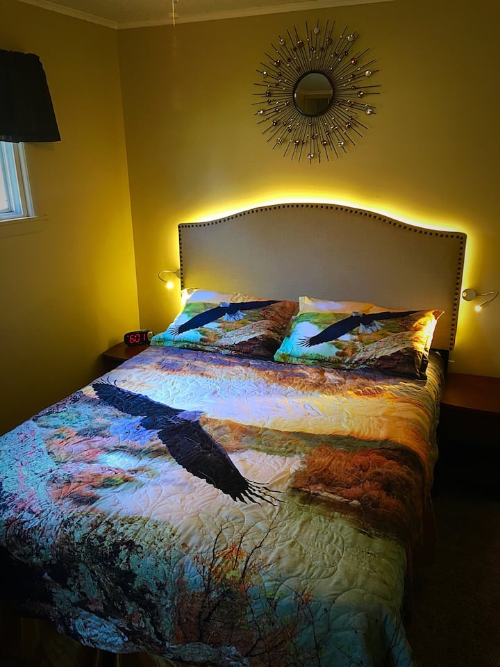 Dormitorio principal con cama queen, iluminación LED y puertos de carga USB (en el reloj)