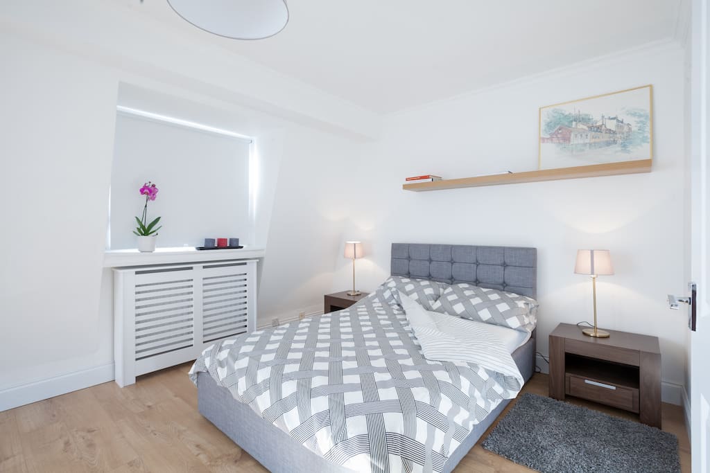 Large bedroom with comfortable bed for 2 people, chest of drawers and storage for beddings.