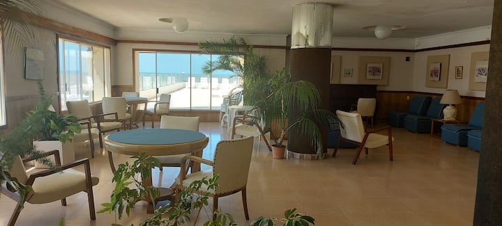 Espacio con sillones y mesas en el entrepiso. Piano. Multiuso. Ventanales con hermosa panorámica de la playa. Afuera... un solarium