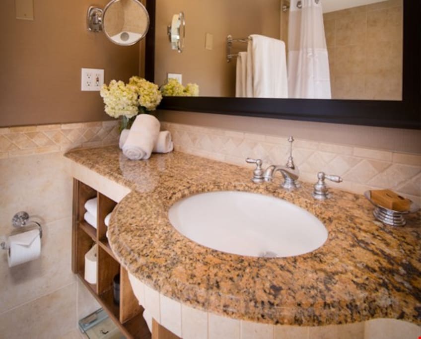 The modern bathroom features pristine granite countertops and marble floors, and comes equipped with plush bathrobes and slippers.