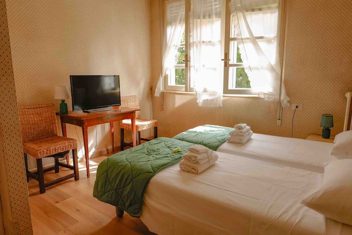 Прва спална соба со два кревета,паметен телевизор, тавански вентилатор, голем вграден плакар  и поглед кон градината.