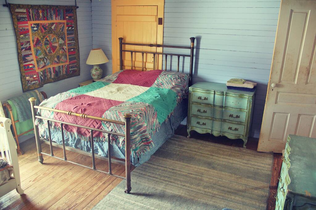 The farm stay bedroom is in the house. It has a double bed, twin bed, couch, desk, and two dressers.