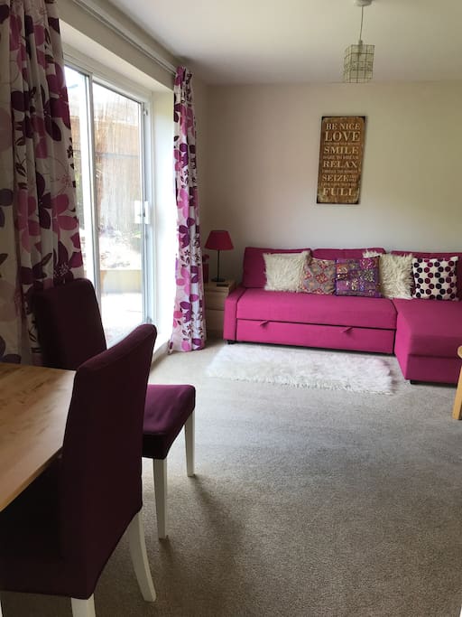 Chaise double sofa bed, bright patio window & dining/laptop desk area.