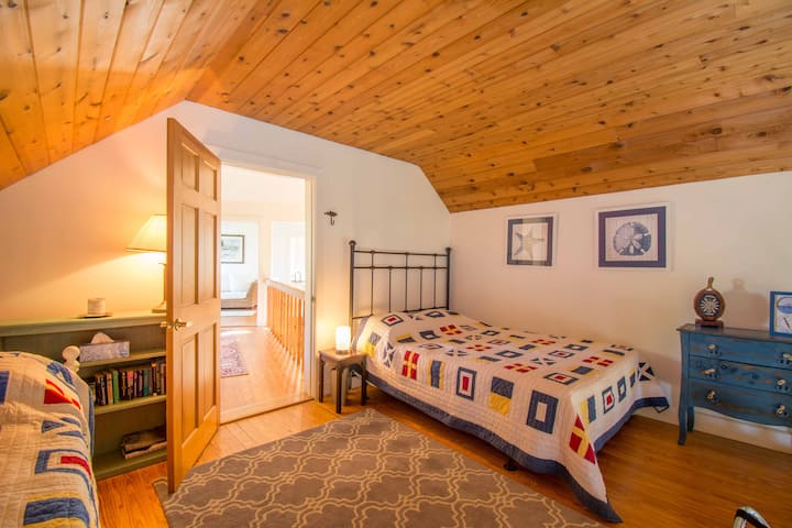 Dormitorio loft con una cama completa y un sofá cama que tiene dos camas individuales.