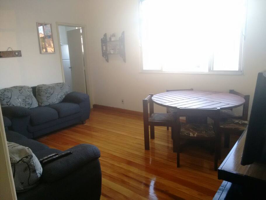 Sala espaçosa com 2 sofás, mesa de jantar grande, rack com TV e janela com vista panorâmica do centro da cidade.
